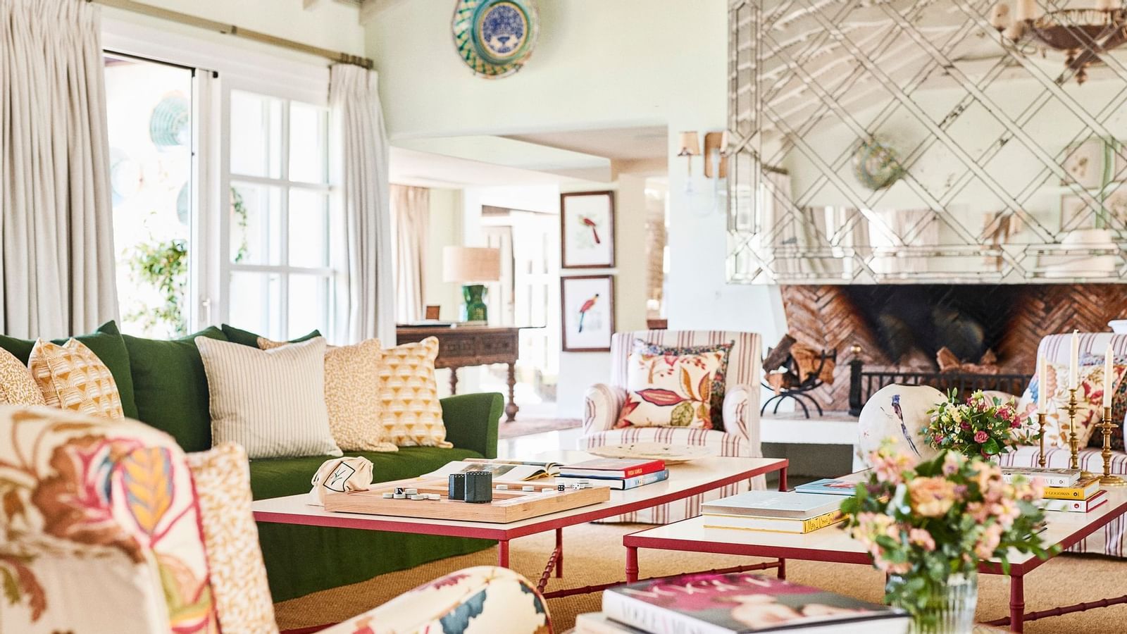 Green sofa and patterned chairs placed around coffee tables, near a mirrored fireplace at the Marbella Club