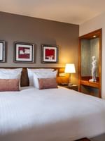 Bed between side tables near statue on a wooden stand in Warwick Suite at Warwick Grand Place Brussels