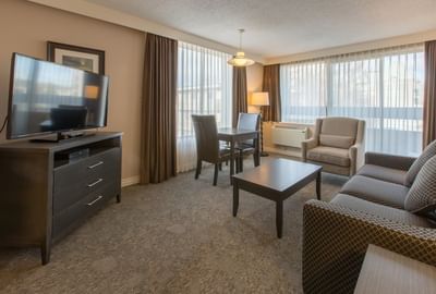 One-Bedroom Suite living area with a comfortable couch, a TV and an armchair at Embassy Inn Victoria