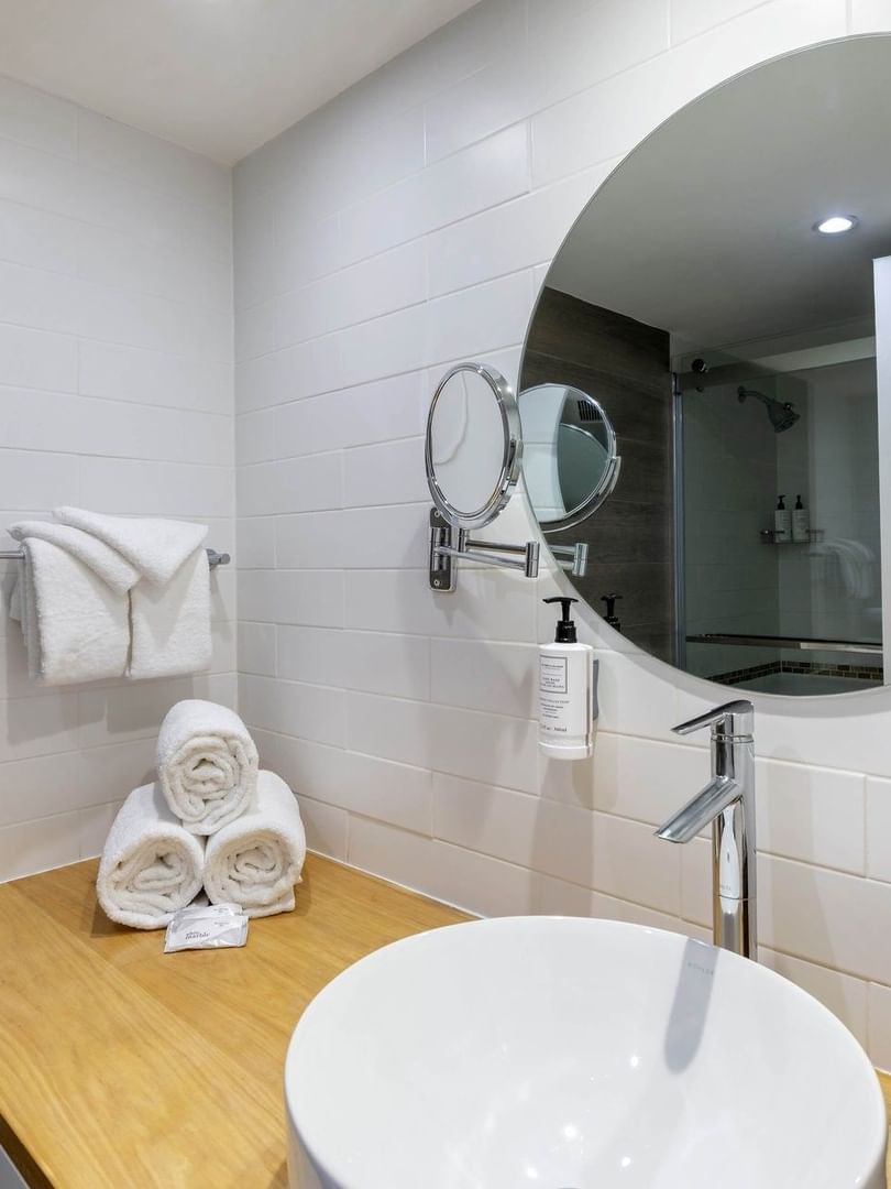 Vessel sink on a wood counter by towels and a Round mirror in Water View at Warwick Paradise Island Bahamas