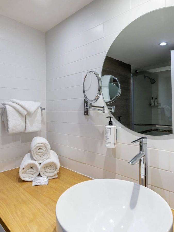 Vessel sink on a wood counter by towels and a mirror in One Bedroom Harbourfront Suite at Warwick Paradise Island Bahamas