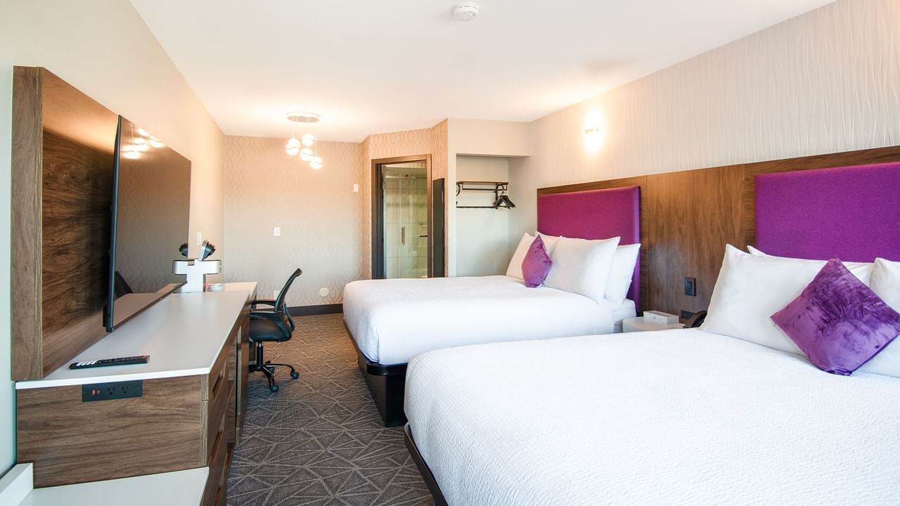 Hotel guest room with two queen beds, flat screen TV, and work desk