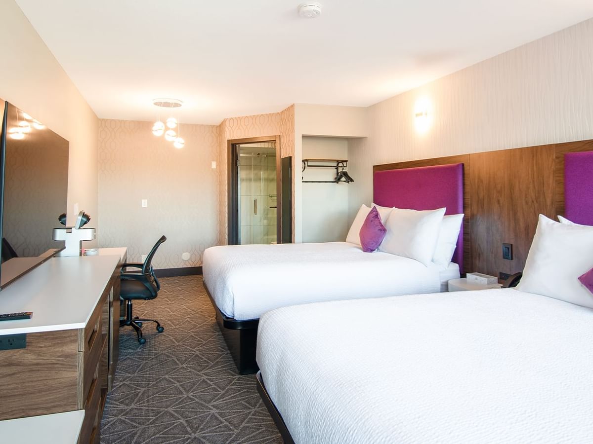 Hotel guestroom with two queen beds, flat screen TV, work desk and chair