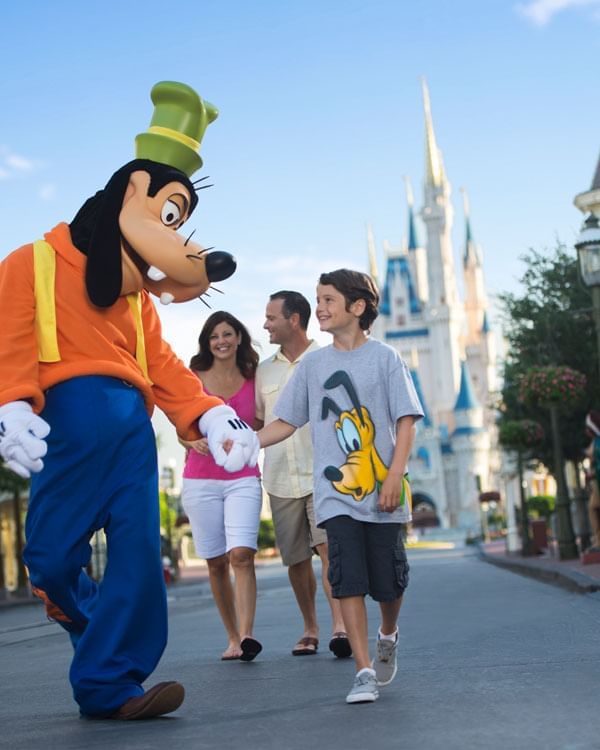 A person in a Goofy costume at a theme park holding hands with a child near Lake Buena Vista Resort Village & Spa