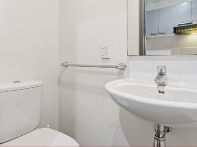 Clean white toilet and sink with silver faucet and towel bar at Student Living Auckland Beach.