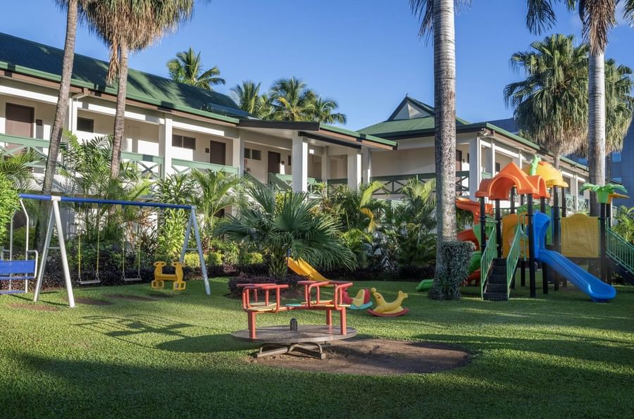 Colorful playground with swings and slides in front of a resort building at Tokatoka Resort.