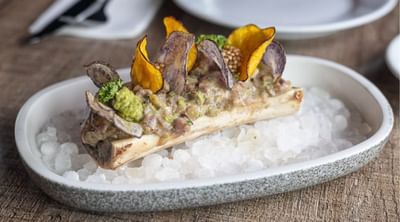 Gourmet dish featuring bone marrow topped with vibrant vegetable chips and garnishes served in Restaurant N3 at Hotel Nodo