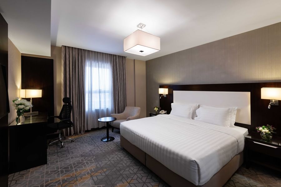 Work desk, nightstand, and cozy lounge chair by the bed in the Family Suite at Warwick Hotel Jeddah