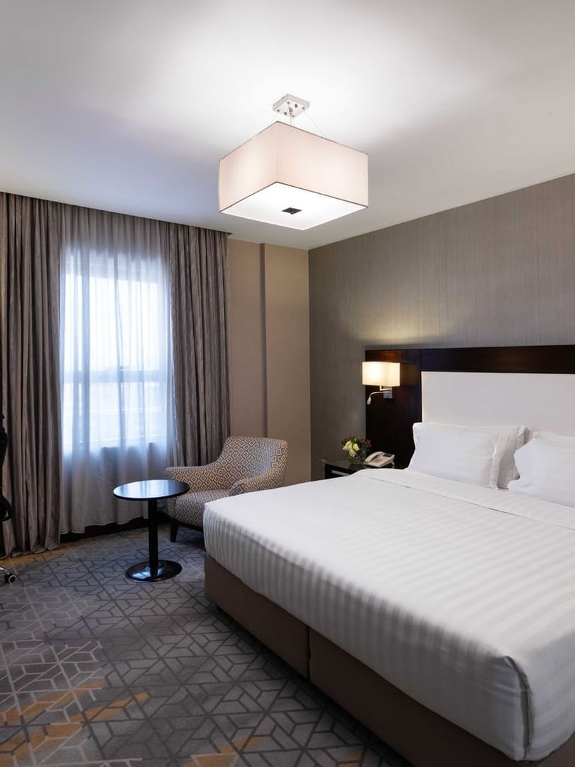 Work desk, nightstand, and cozy lounge chair by the bed in the Family Suite at Warwick Hotel Jeddah