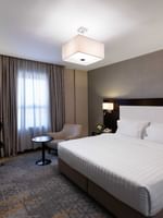 Work desk, nightstand, and cozy lounge chair by the bed in the Family Suite at Warwick Hotel Jeddah