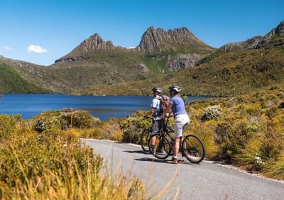 2 People on mountain bikes by a lake near Cradle Mountain Hotel