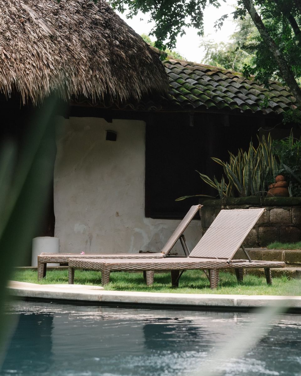 Poolside lounge chairs under a thatched hut at Morgan\'s Rock, a sustainable jungle lodge near San Juan del Sur