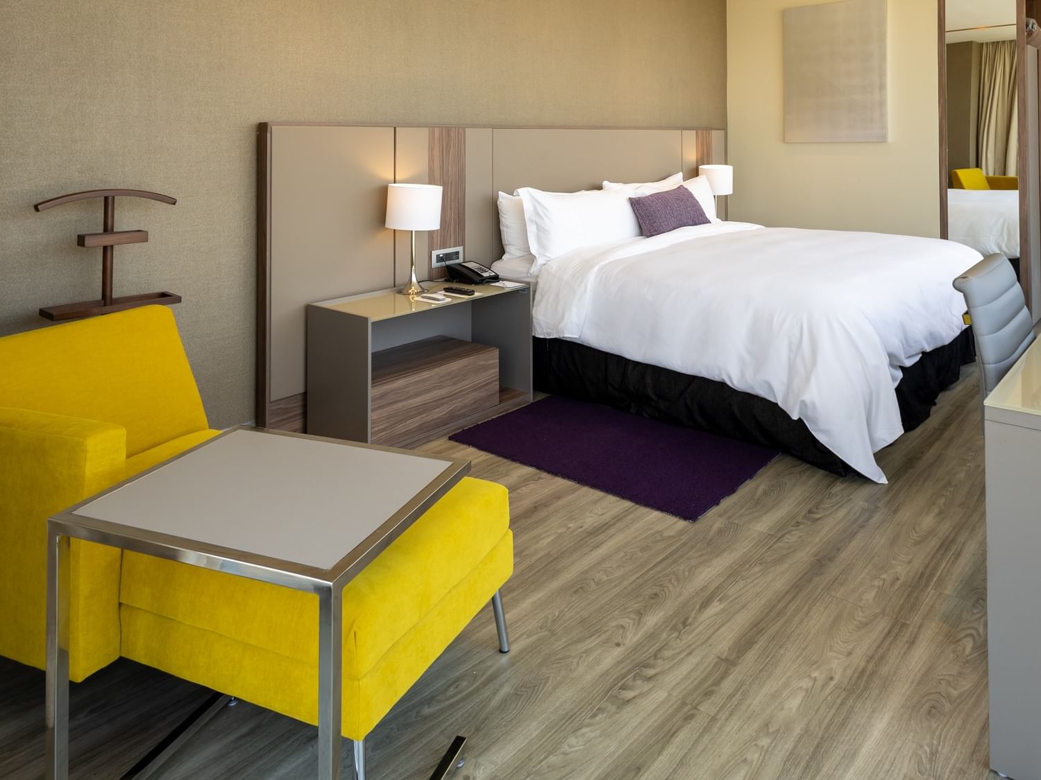 Junior Suite King con cama king, sillón amarillo y decoración moderna en Camino Real Fashion Drive Monterrey.