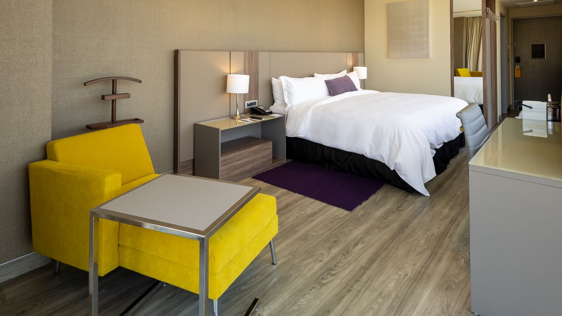 Junior Suite King con cama king, sillón amarillo y decoración moderna en Camino Real Fashion Drive Monterrey.