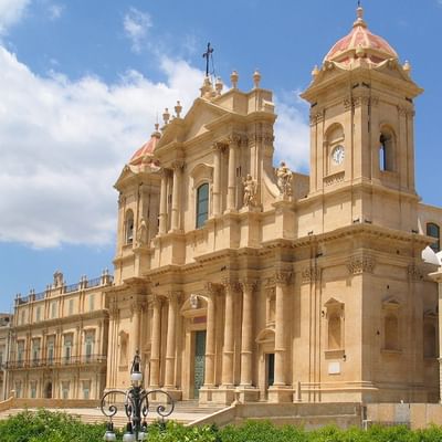 Barocke Kathedrale mit zwei Türmen und einer Kuppel, umgeben von üppigem Grün.