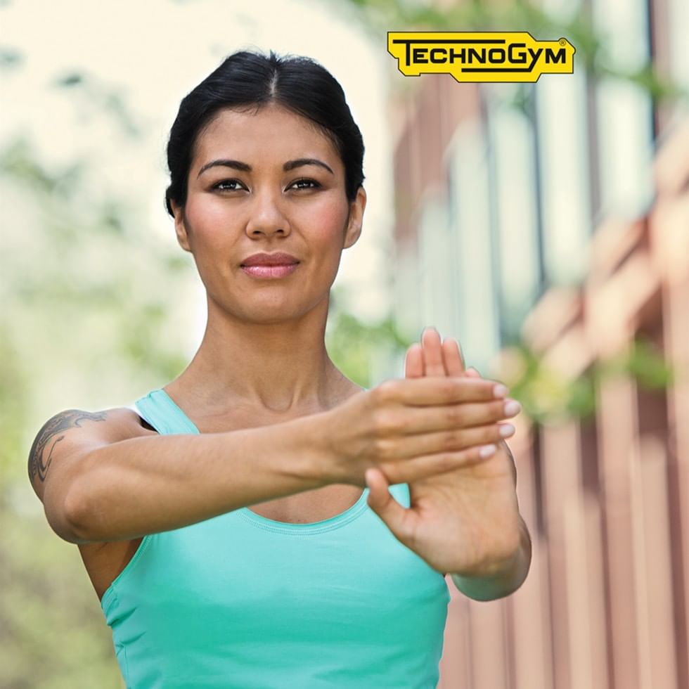 Woman in a teal tank top doing a workout pose with hands clasped,