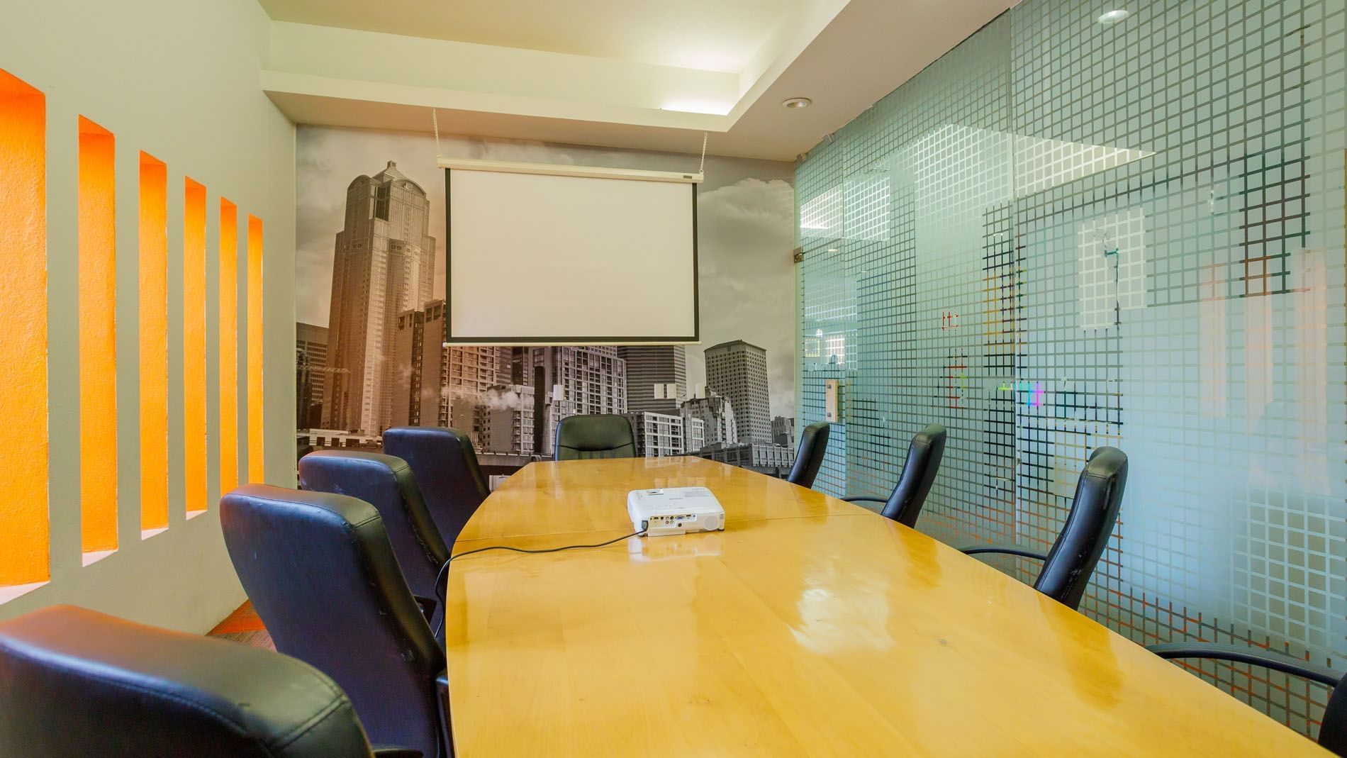Professional boardroom including a long wooden table, projector screen, and frosted glass at Real Inn Torreon