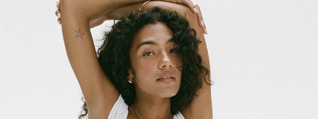 Olivia Dean with curly hair and star tattoo on her arm promoting The Art of Loving Tour 2026.