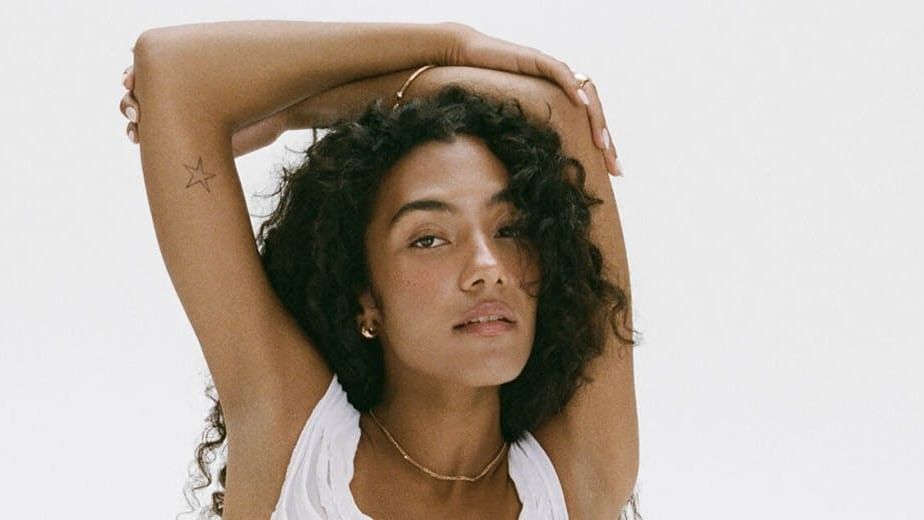 Olivia Dean poses with arms raised behind her head for The Art of Loving Tour 2026.