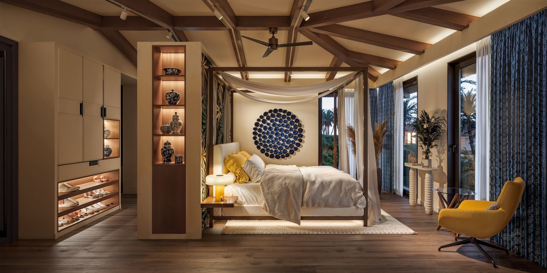 Four-poster bed with canopy next to a yellow armchair in a luxury guest bedroom suite within Golden Rock Resort