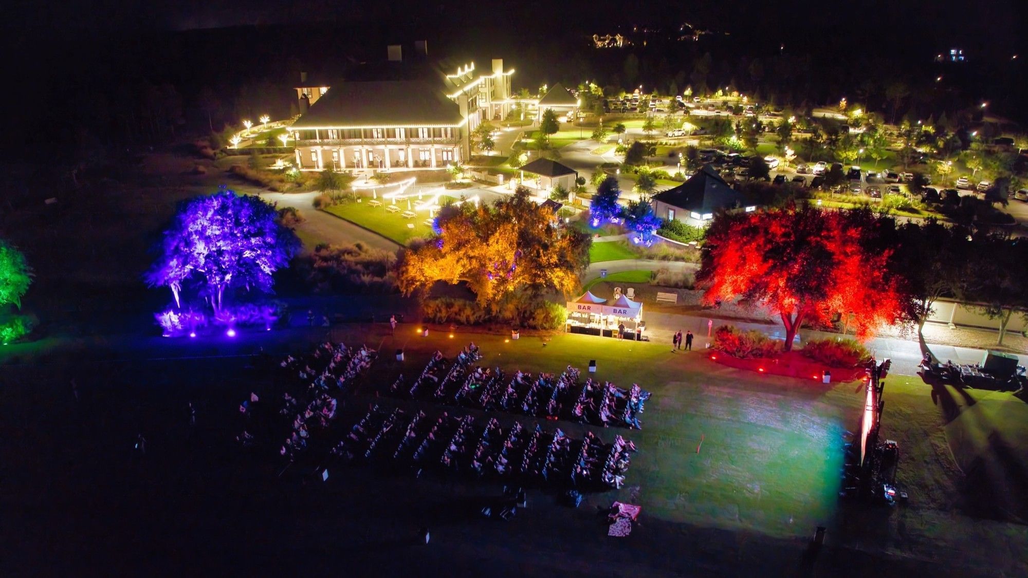 Aerial view of Camp Creek Inn with illuminated trees and a crowd gathered for an event.