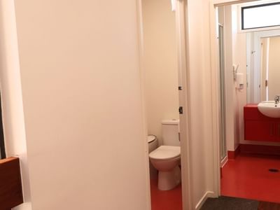 Red and white bathroom with toilet and sink at La Trobe University Hillside Apartments.