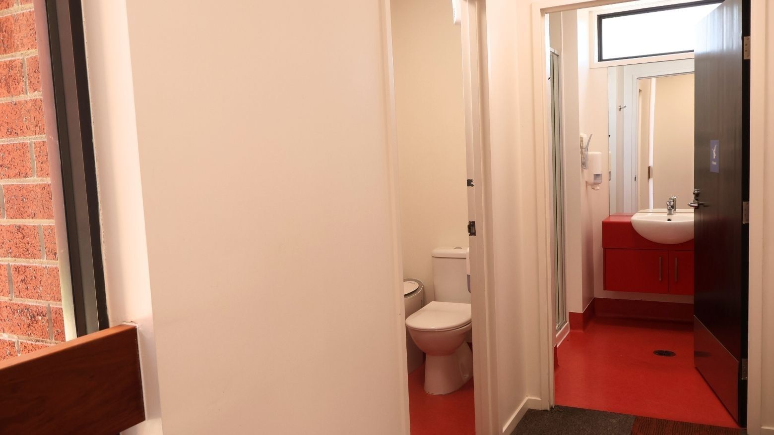 Red and white bathroom with toilet and sink at La Trobe University Hillside Apartments.