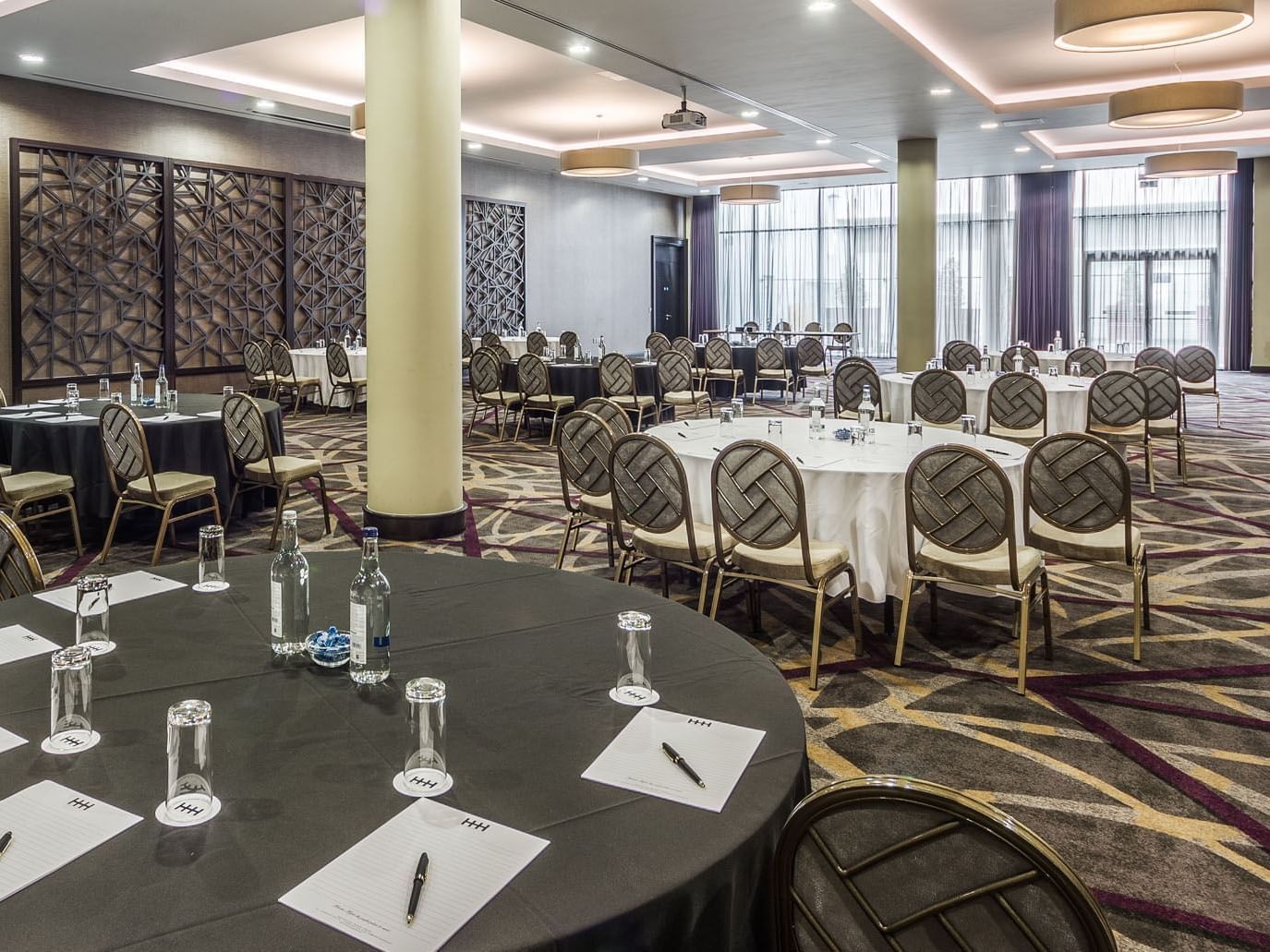 Elegant conference room featuring round tables set for meetings, with decor and large windows at the Heston Hyde Hotel