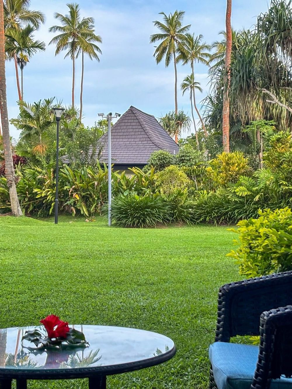 Chairs and table with a red flower on the lawn at The Naviti Resort in Korolevu.