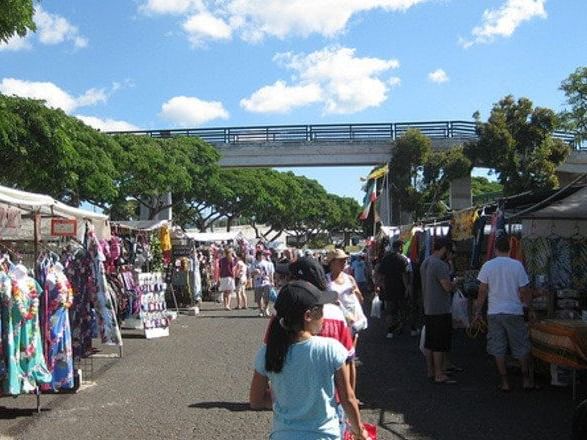 People walking and gathered in Aloha Stadium Swap Meet near Waikiki Resort Hotel by Sono