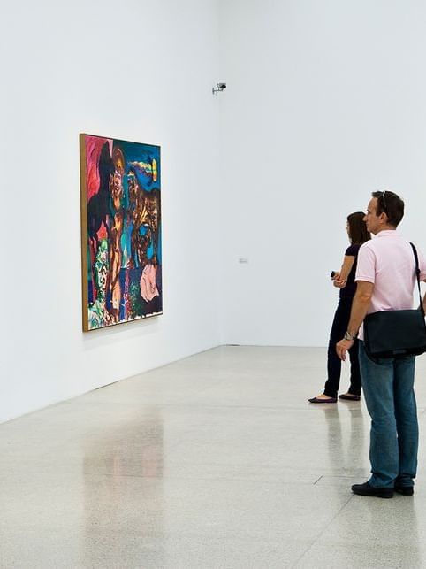 Visitors looking at large, colorful abstract paintings placed on white gallery walls near Hotel Westminster Paris