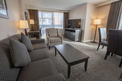 One-Bedroom Suite living area with a comfortable couch, a TV and an armchair at Embassy Inn Victoria