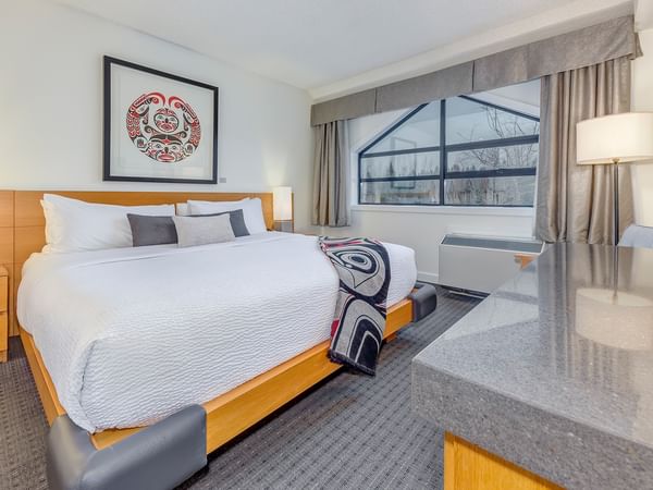 Hotel room with large bed, nightstands, and a desk with a window view.