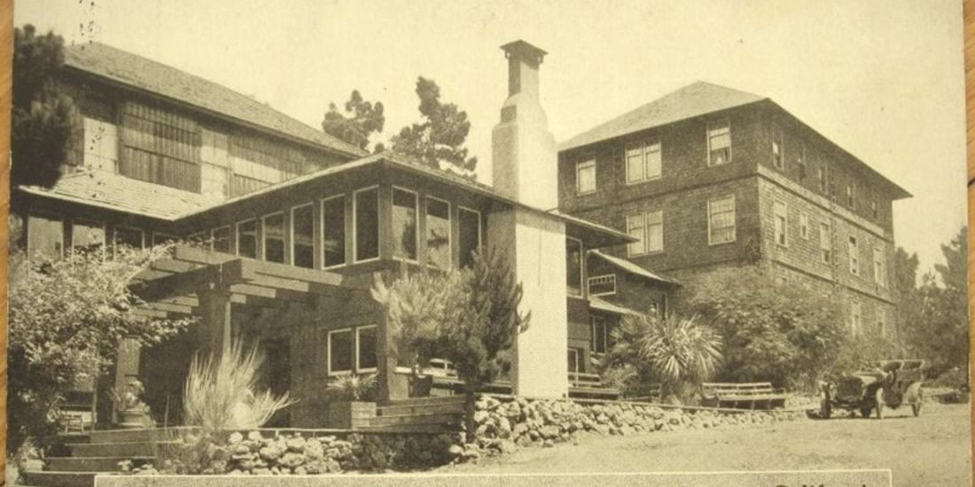 Historic black and white photo of Pine Inn, surrounded by trees and parked vintage cars