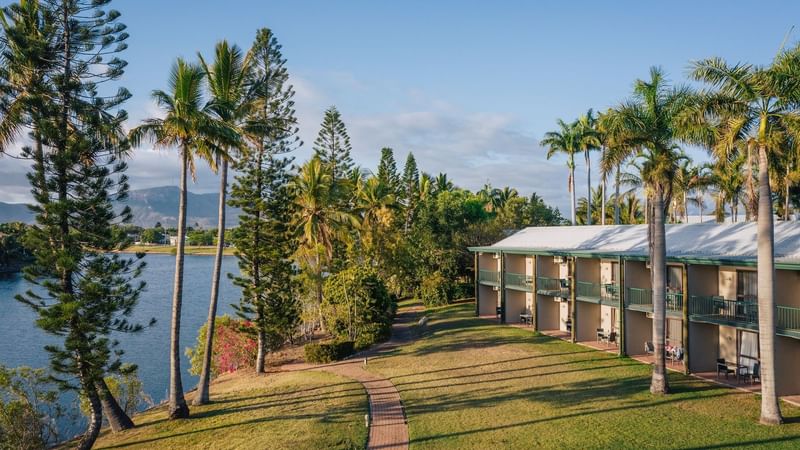 Scenic view of Mercure Hotel Townsville's Outdoor Spaces surrounded by lush trees under clear blue skies