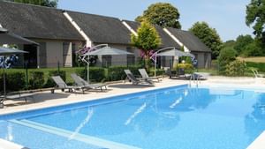 Outdoor pool with sun loungers at The Originals Hotels