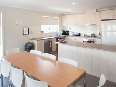 Dining table with eight chairs in the kitchen area of La Trobe University Regional Housing.