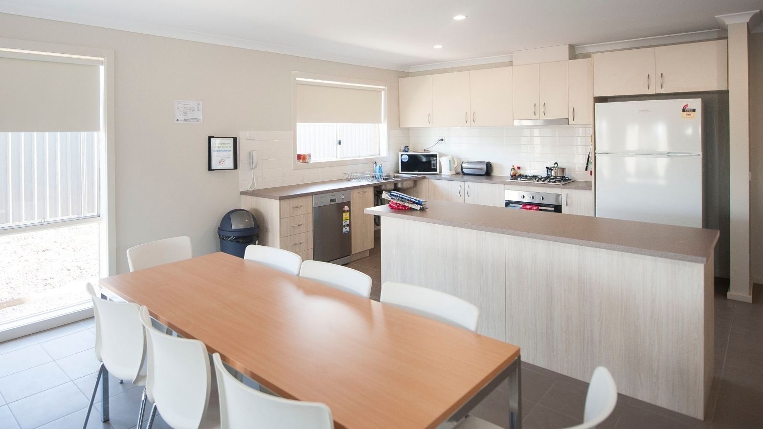 Dining table with eight chairs in the kitchen area of La Trobe University Regional Housing.