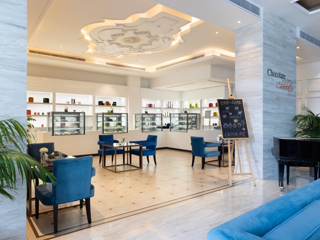 Chocolate Café featuring blue chairs by white shelving units and a chalkboard easel at Warwick Al Khobar