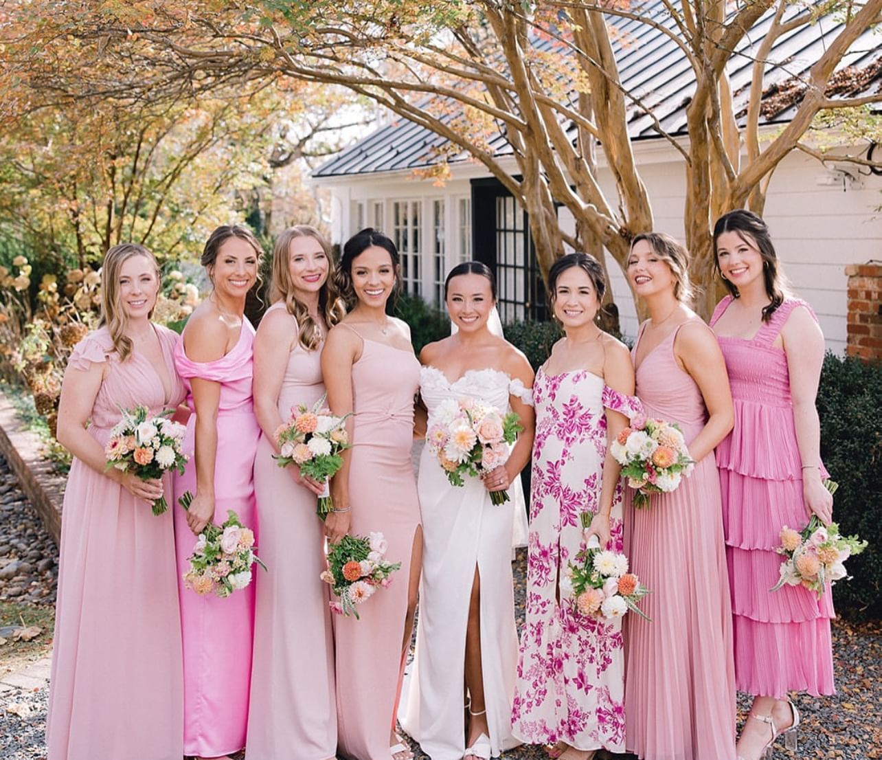 Bridesmaids and bride in pink dresses holding floral bouquets in front of the Clifton Hotel in Charlottesville, VA.