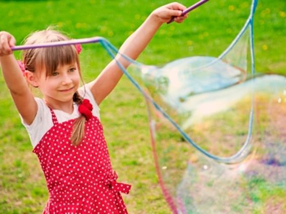 Little girl happily plays with a soap bubble at Fairmont Hot Springs Resort