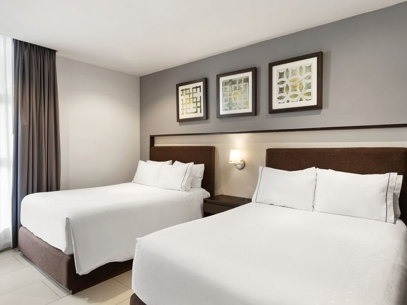 Luxury Suite featuring two white cozy linen beds, grey walls, and framed geometric wall art at Sunvivia Mazatlán