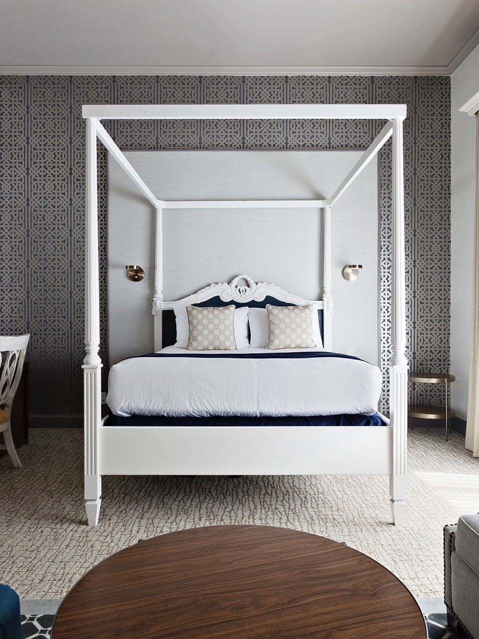 Four-poster bed by a desk and grey sofa under a patterned wall in Balcony Junior Suite at Warwick San Francisco