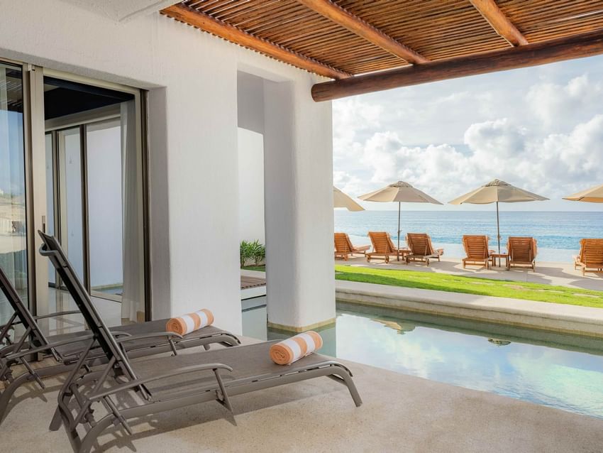 Poolside lounge chairs and more lounge chairs with umbrellas in ocean front in Casita Ocean View at Marquis Los Cabos Resort
