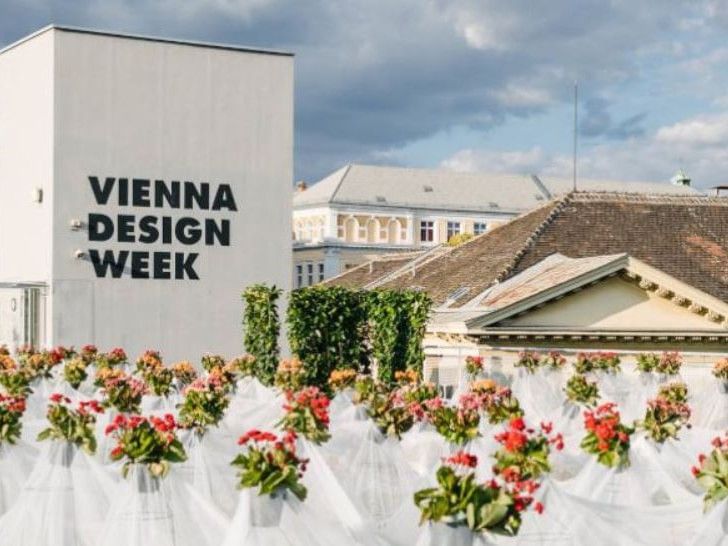 Gebäude mit Aufschrift „Vienna Design Week“ und Blumeninstallation im Vordergrund.