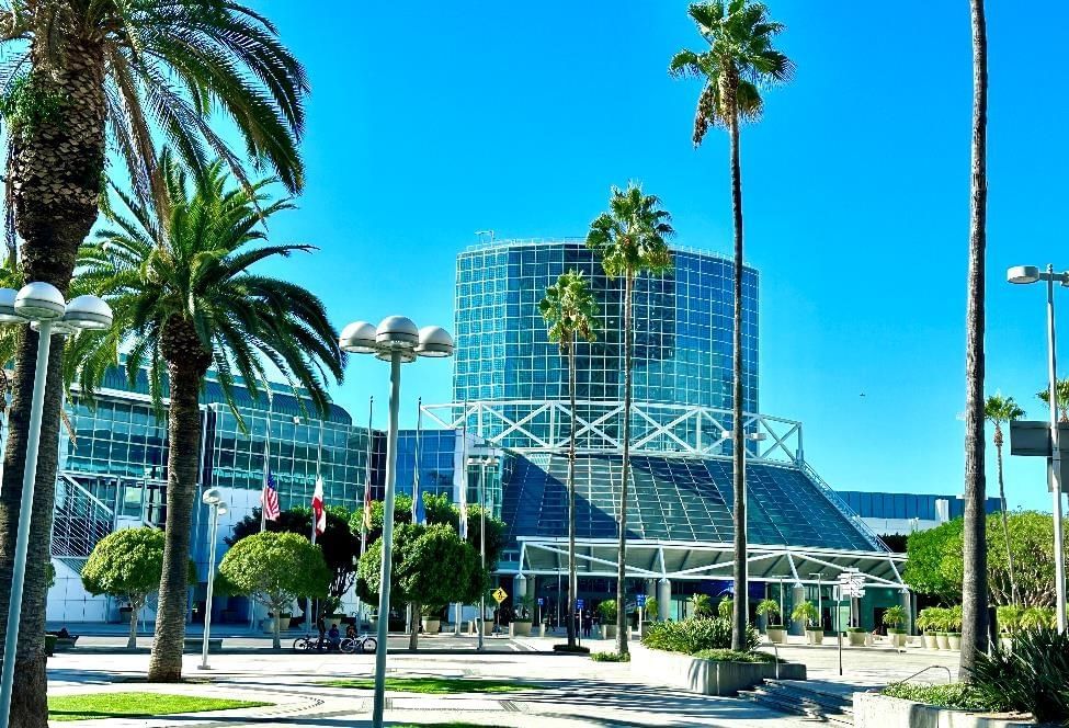 A large glass building with palm trees in front of it.