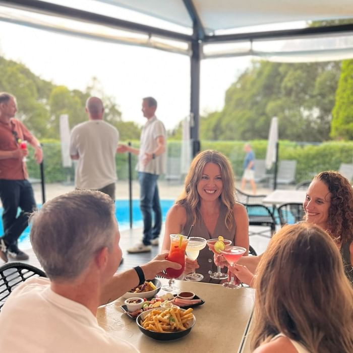 Group dining poolside with cocktails and fries at Mercure Charlestown.