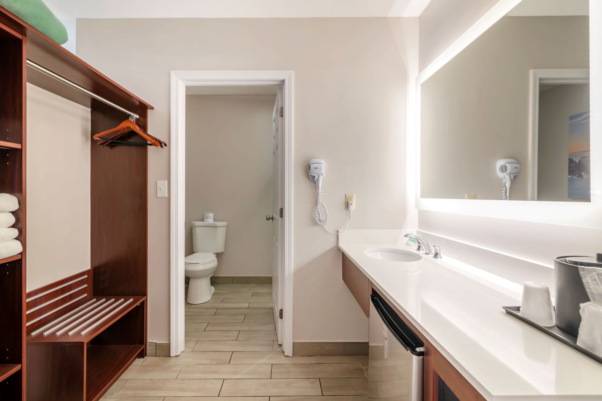 A hotel bathroom with a vanity, mirror, and closet