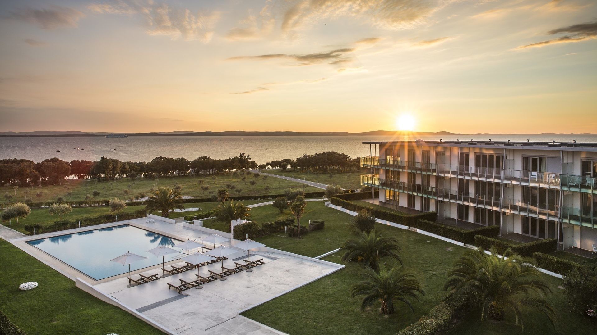 Sonnenuntergang über einem Hotel mit Pool und Meerblick.