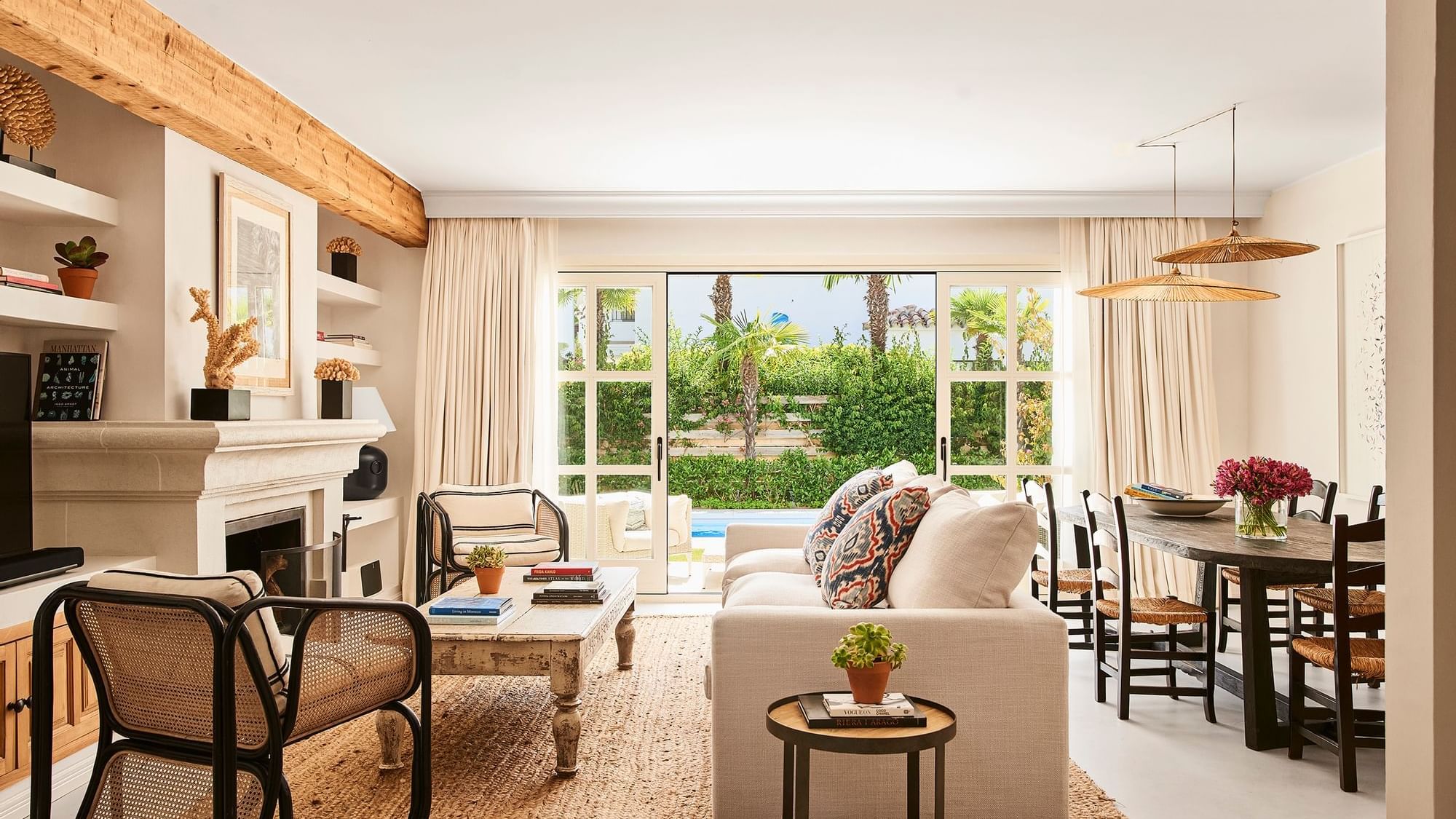 Three-Bedroom Villa living room with wood beams, a fireplace, & open doors leading to a patio & pool at Marbella Club